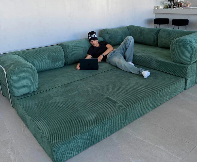 A spacious sage green L-shaped sectional sofa with corded upholstery and modular cushions